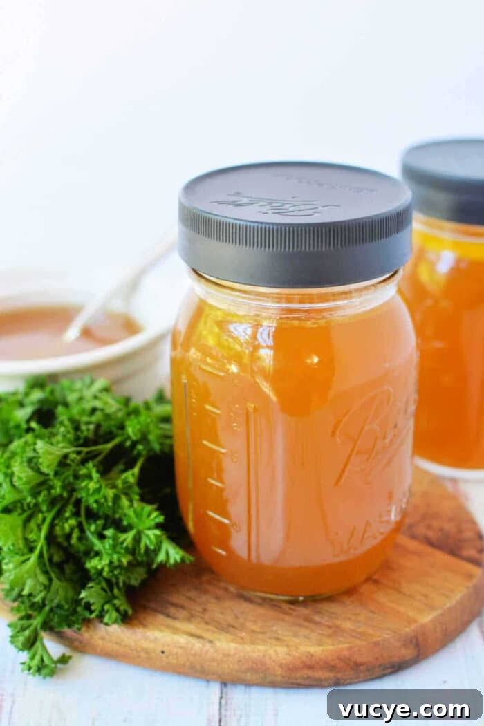 A mason jar of golden bone broth slow cooker on a wooden board, with fresh parsley and a bowl in the background.
