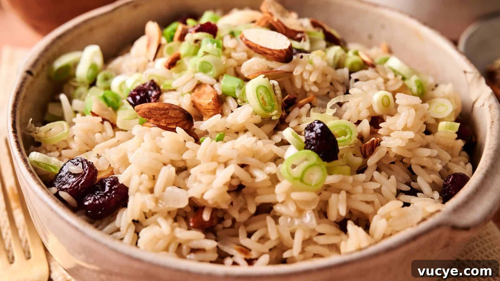A bowl of rice pilaf topped with sliced green onions, almonds, and dried cranberries.