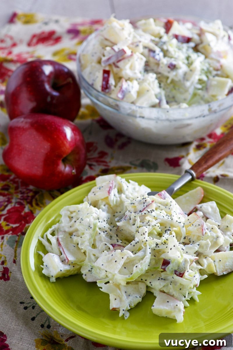 Apple Cole Slaw serving of apple cole slaw on a green plate. cole slaw bowl in background as well as red apples