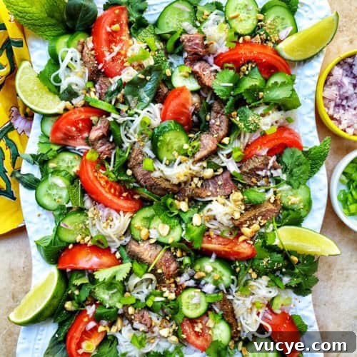 Thai beef noodle salad with tomatoes, cucumbers, and limes.