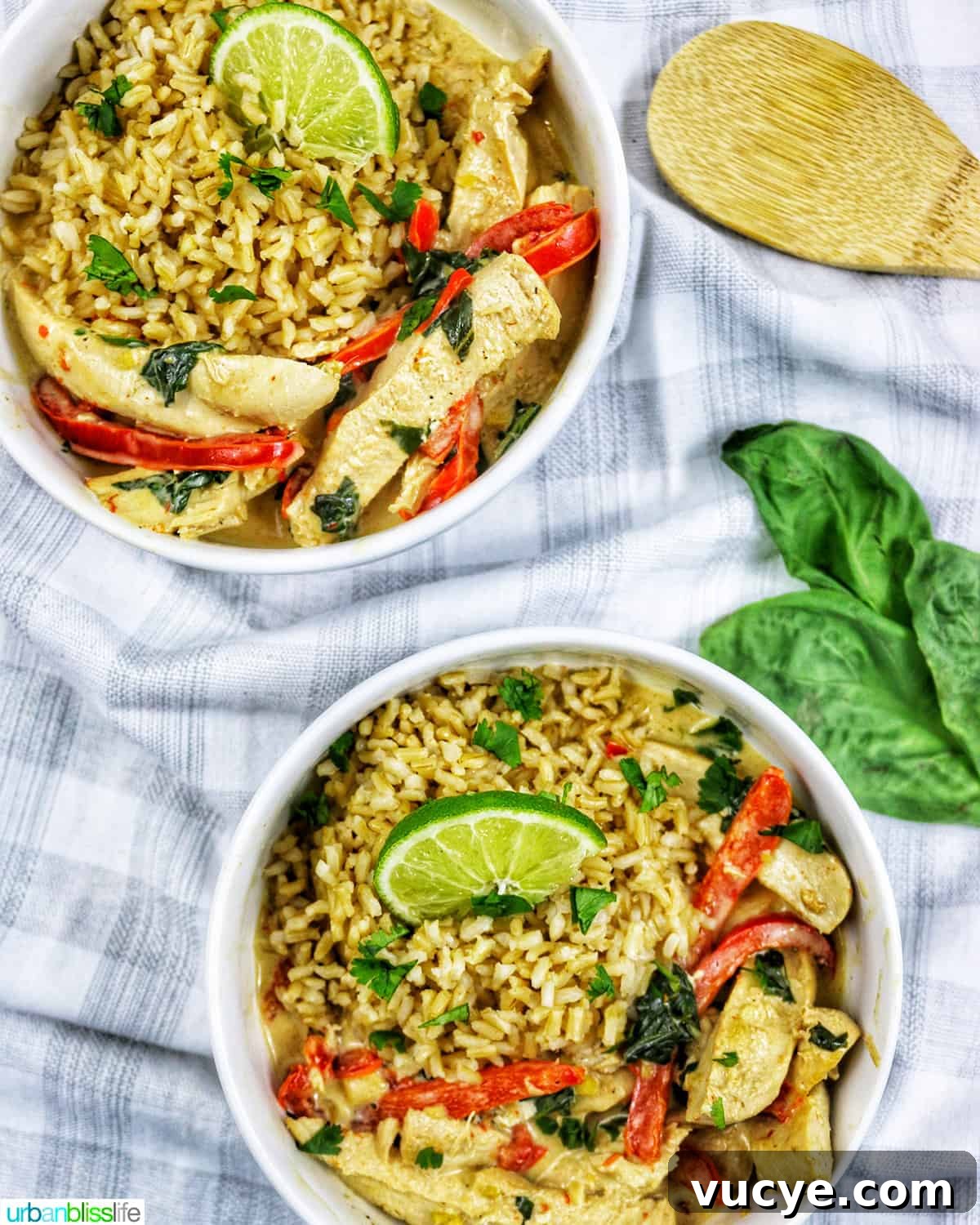 two bowls of Thai coconut lime chicken with red bell pepper slices and lime slices over rice.
