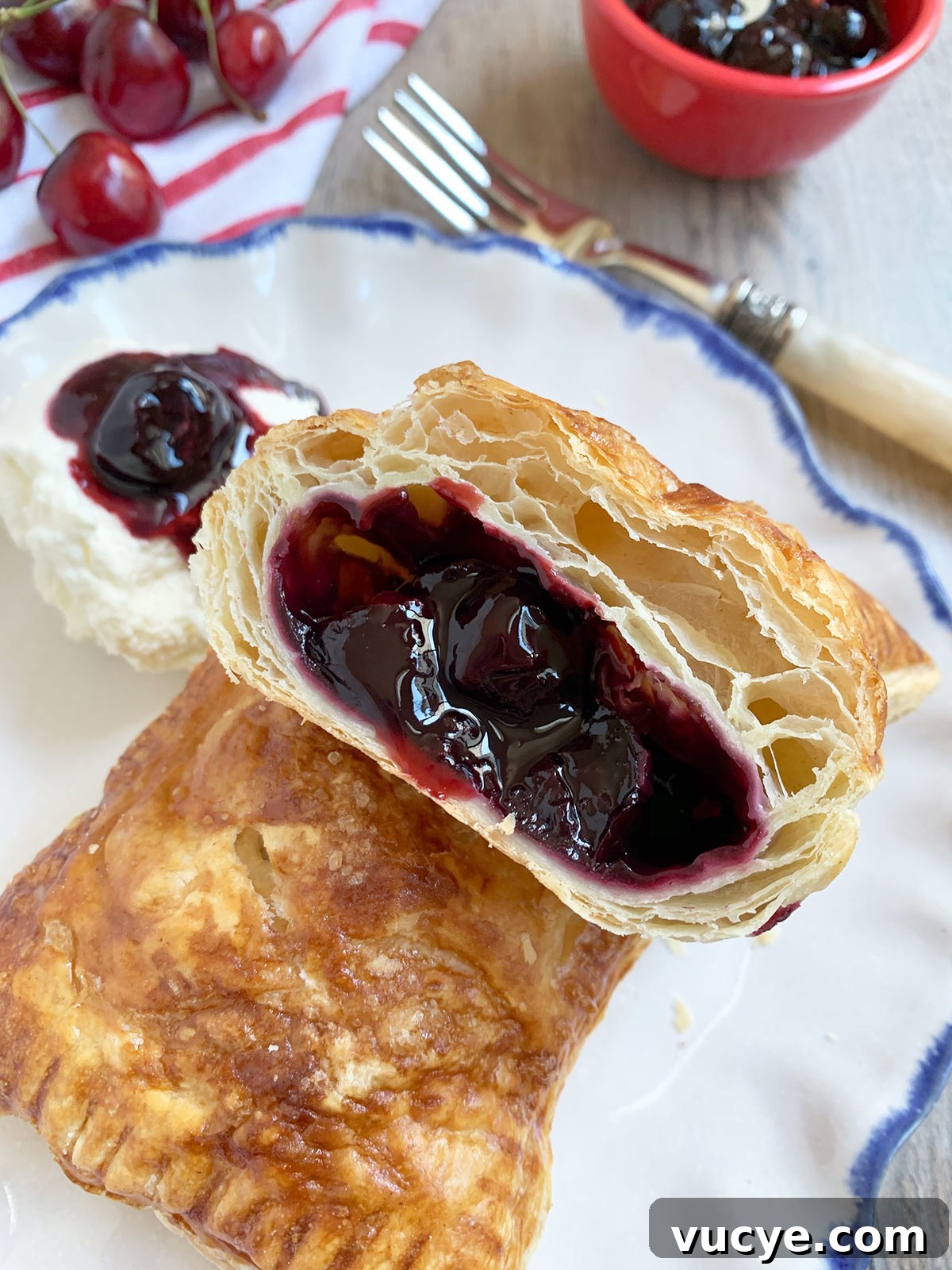Mini Cherry Hand Pies: Bite-Sized Fruit Pastries Recipe 8 Puff pastry mini cherry pie cut open on blue rimmed plate.