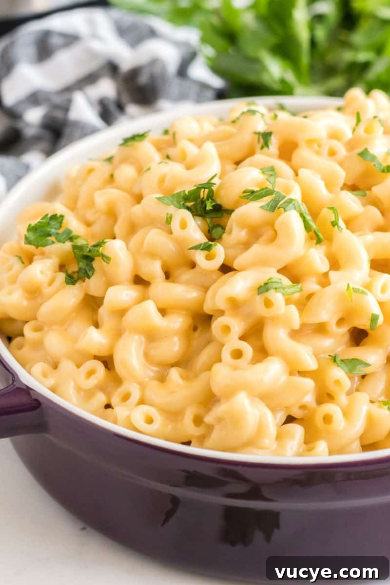 Macaroni and cheese is total comfort food! This easy Instant Pot Mac and Cheese recipe is ready in 30 mins for a dinner your family will love! serving bowl of instant poc mac and cheese with chopped parsley on top