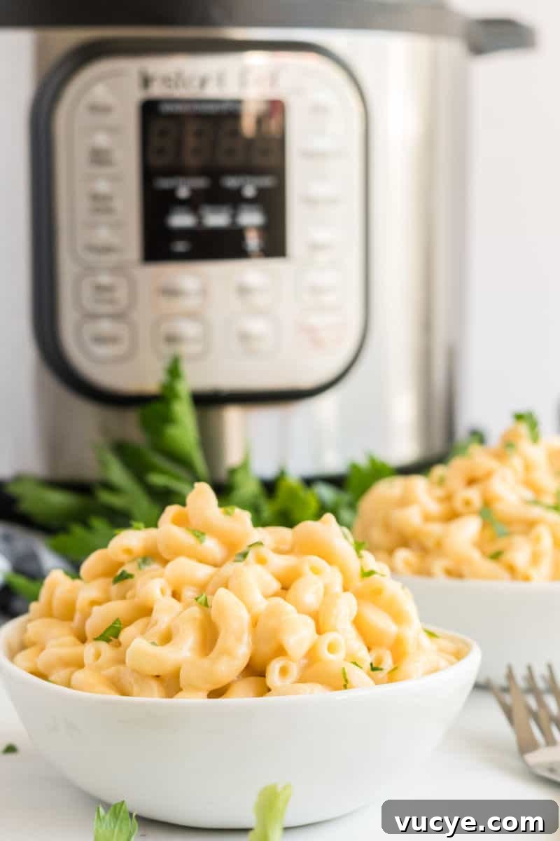 Macaroni and cheese is total comfort food! This easy Instant Pot Mac and Cheese recipe is ready in 30 mins for a dinner your family will love! bowls of mac and cheese in front of an instant pot