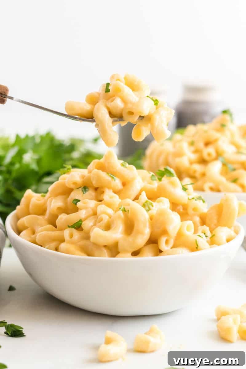 Macaroni and cheese is total comfort food! This easy Instant Pot Mac and Cheese recipe is ready in 30 mins for a dinner your family will love! forkful of mac and cheese over a bowl