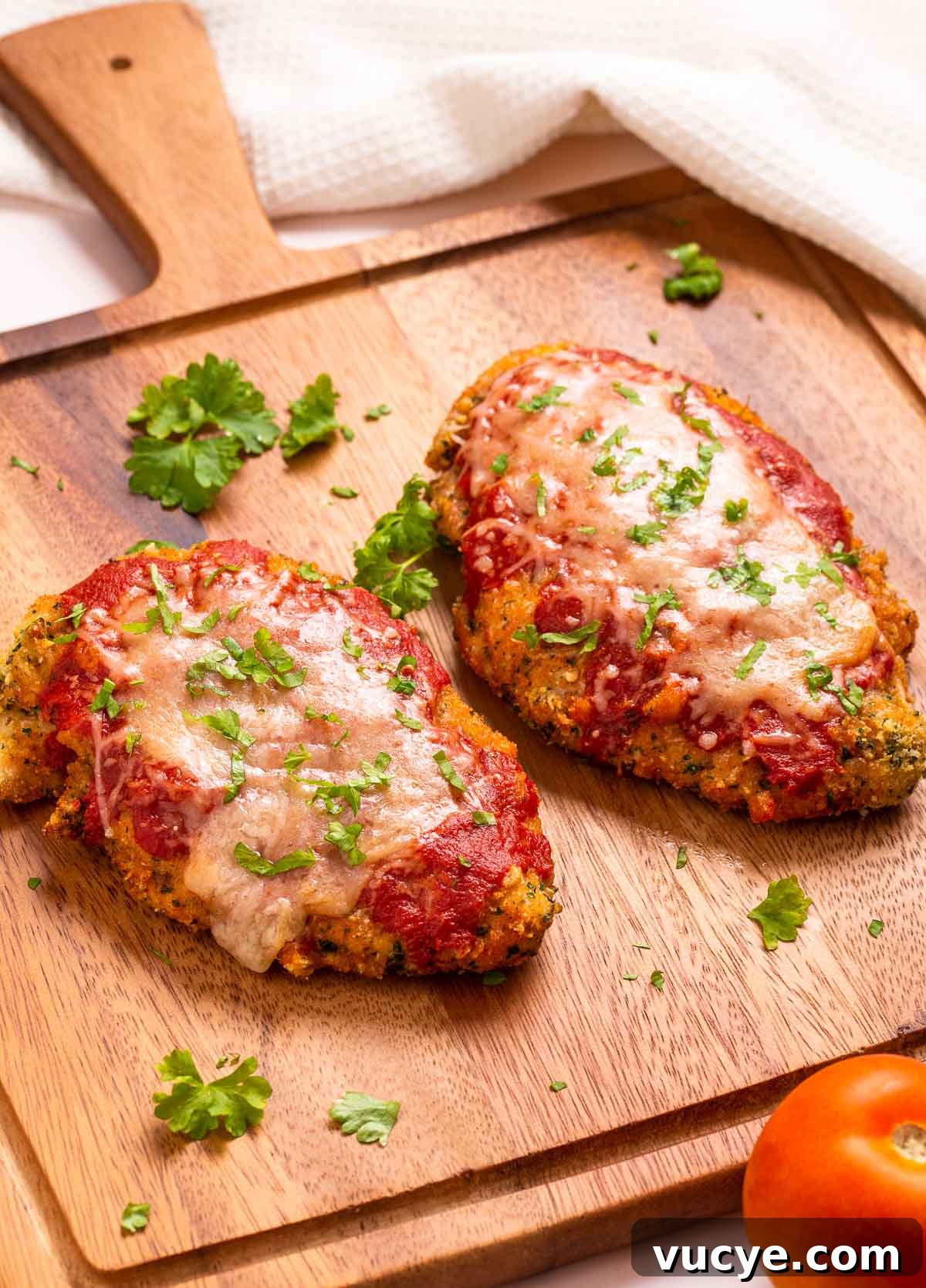 Two low carb breaded and air-fried chicken parmesan cutlets with marinara sauce and cheese.