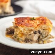 A slice of a chicken pot pie with a bacon biscuit crust.