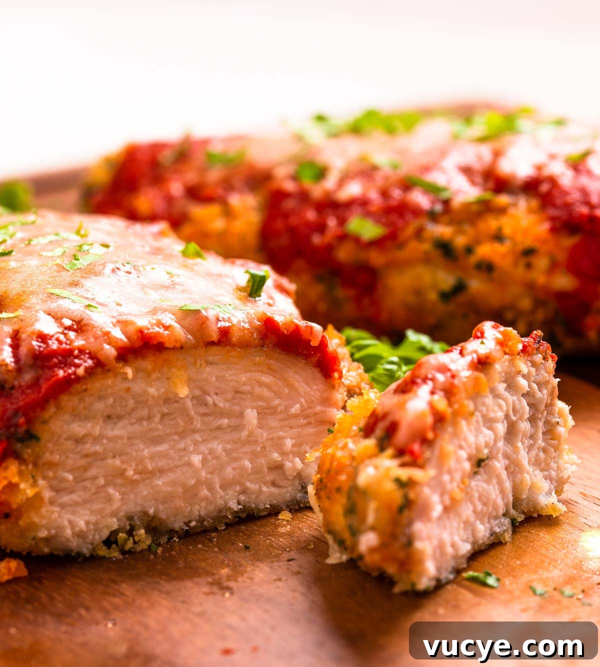 Two low carb breaded and air-fried chicken parmesan cutlets with marinara sauce and cheese.