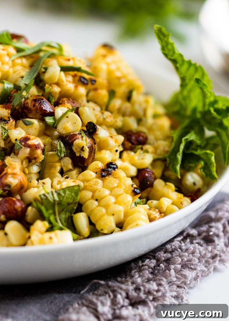 close up: grilled corn salad with hazelnuts with fresh herbs in a white bowl