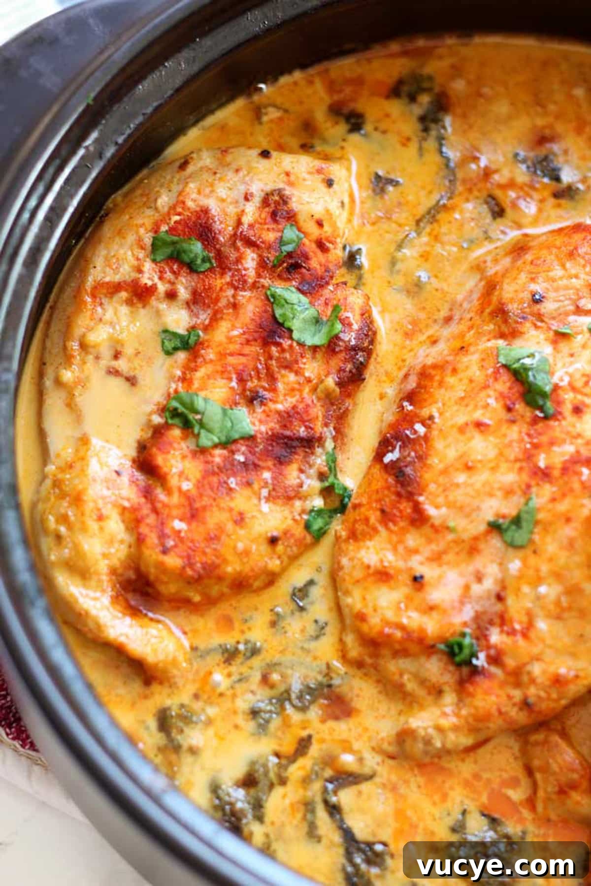 Black pot containing 3 breasts of lemon butter chicken, topped with parsley.
