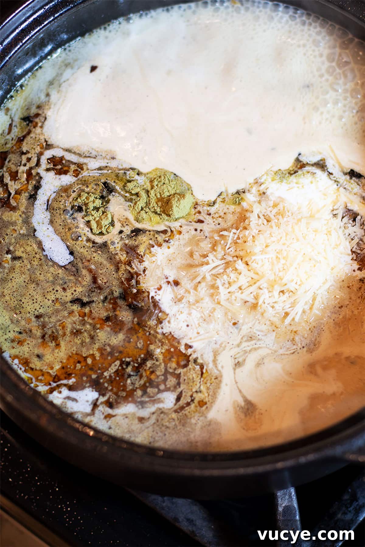 Lemon butter cream sauce in a black pan containing thyme, Parmesan cheese and heavy cream.