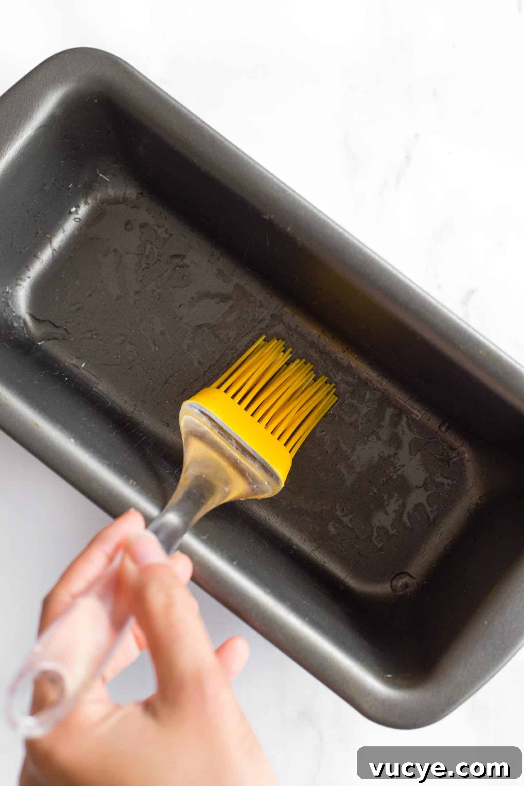 Easy Flaxseed Bread (Gluten-Free, Dairy-Free) Using a silicon brush to grease a metal loaf pan.