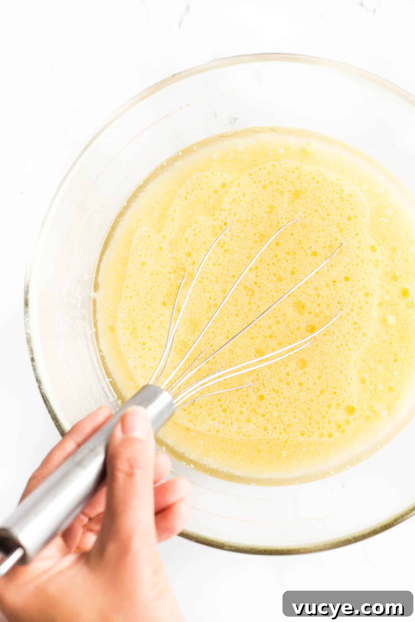 Bread Recipe with Flaxseed Meal (Gluten-Free, Dairy-Free) Whisking pale yellow liquid mixture in a glass bowl.