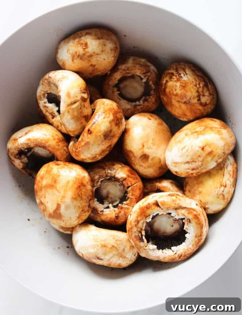Italian-Style Stuffed Mushrooms with Garlic & Parmesan 5 marinating mushroom caps in white bowl