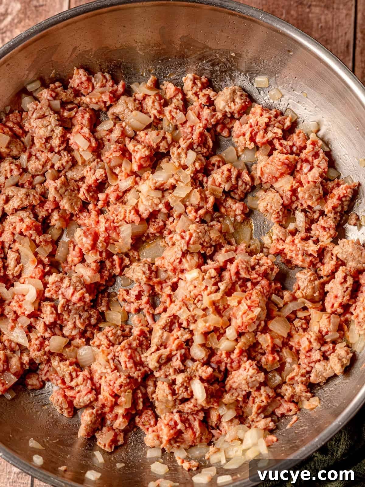 Diced onion and sausage in a skillet.