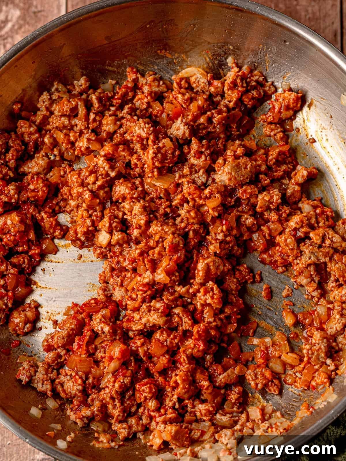Italian sausage in a pan with onion and tomato paste.