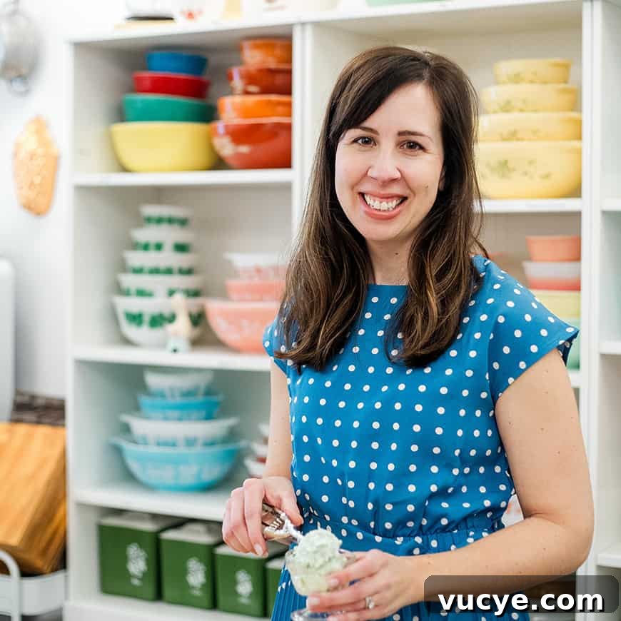 woman scooping pistachio salad into a parfait dish, with colorful vintage bowls in the background.