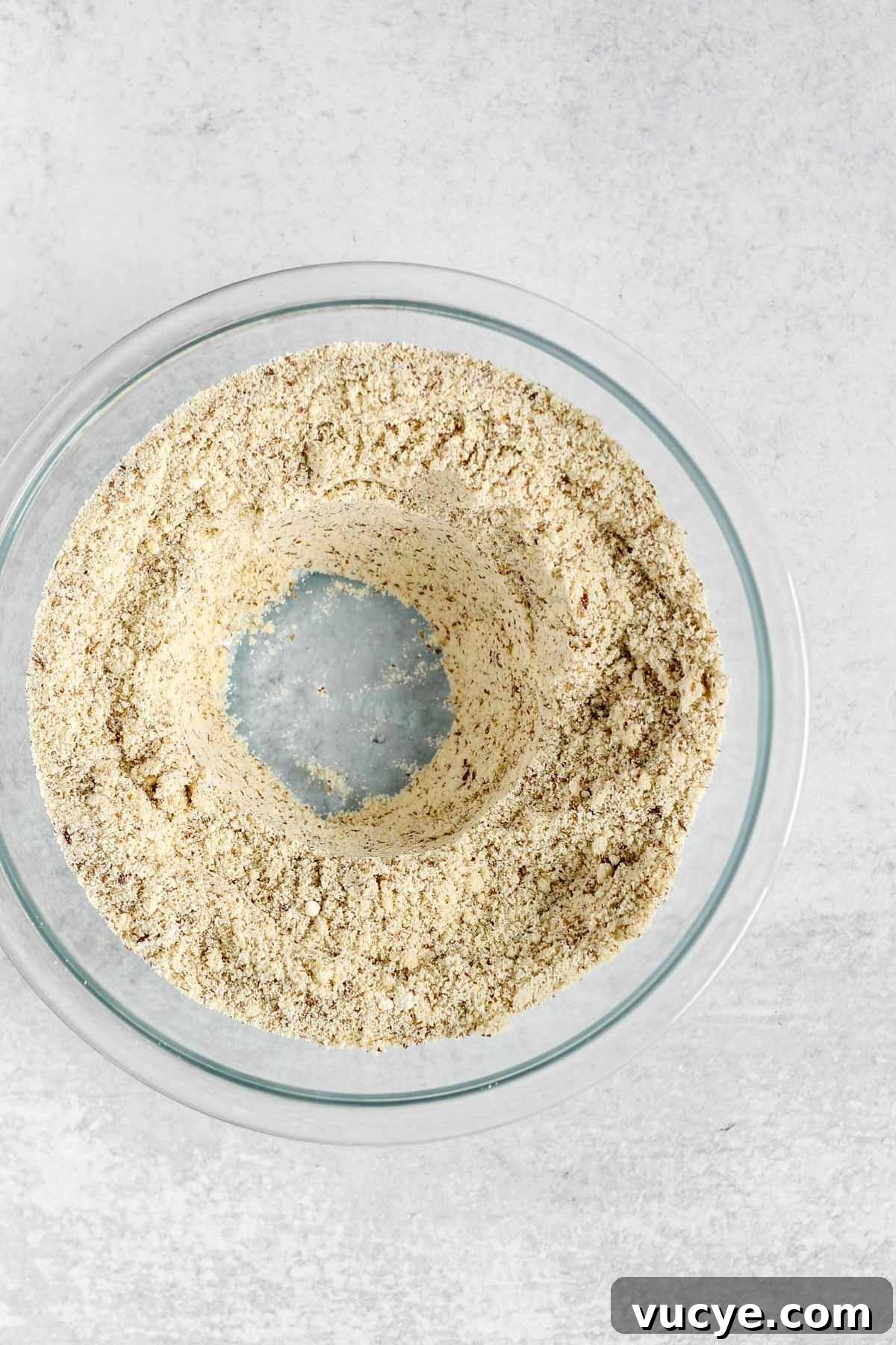 Dry ingredients for almond flour bread, with a well in the center, in a glass mixing bowl.