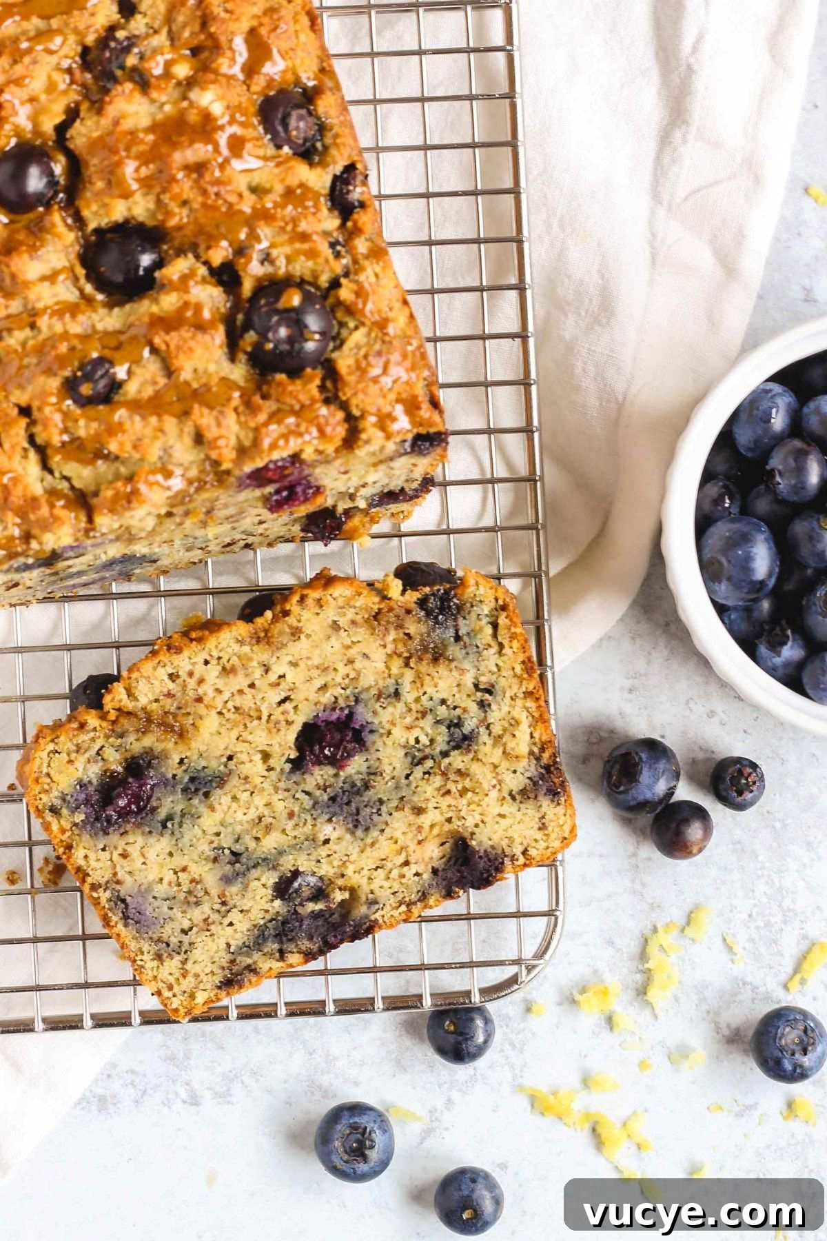 Blueberry lemon almond flour bread with one slice cut from the loaf on a wire cooling rack.