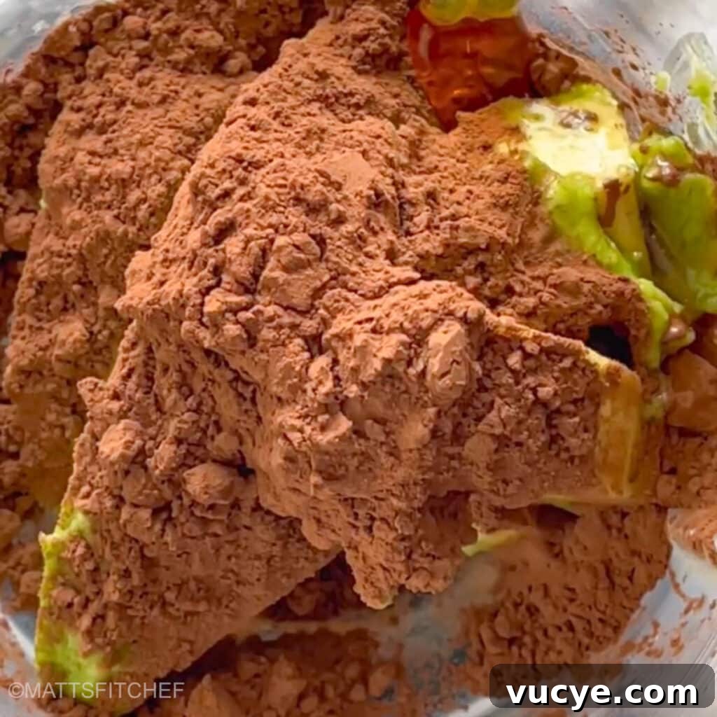 Diced avocados, unsweetened cocoa powder and maple syrup in a blender, ready to pulse until smooth