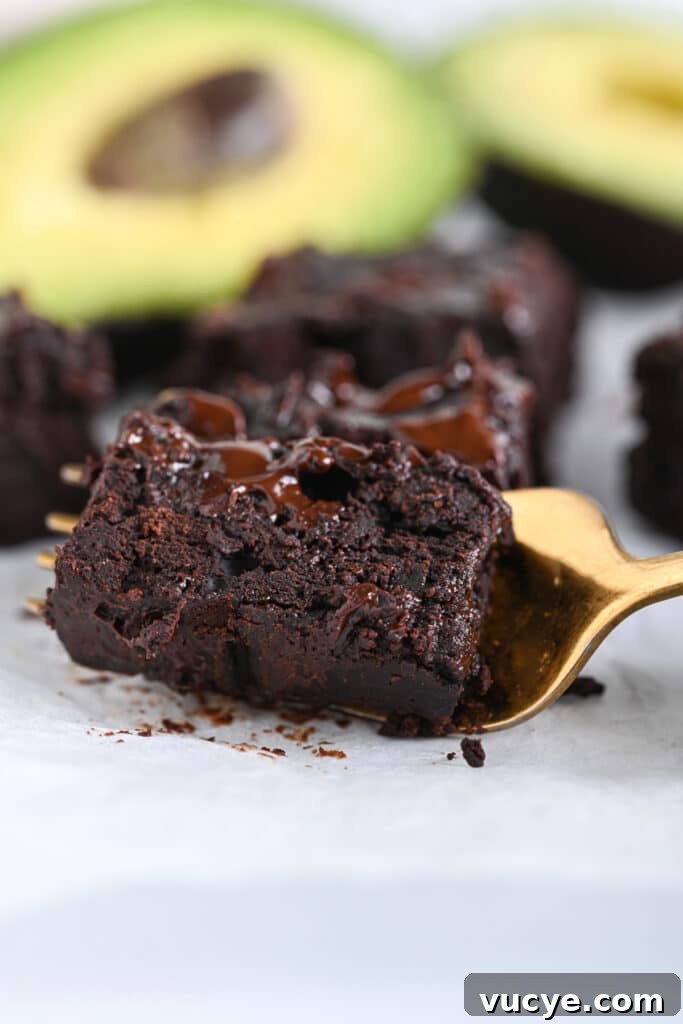 Trying texture of 3 ingredient avocado brownies with a golden fork – they are fudgy, rich and chocolatey.