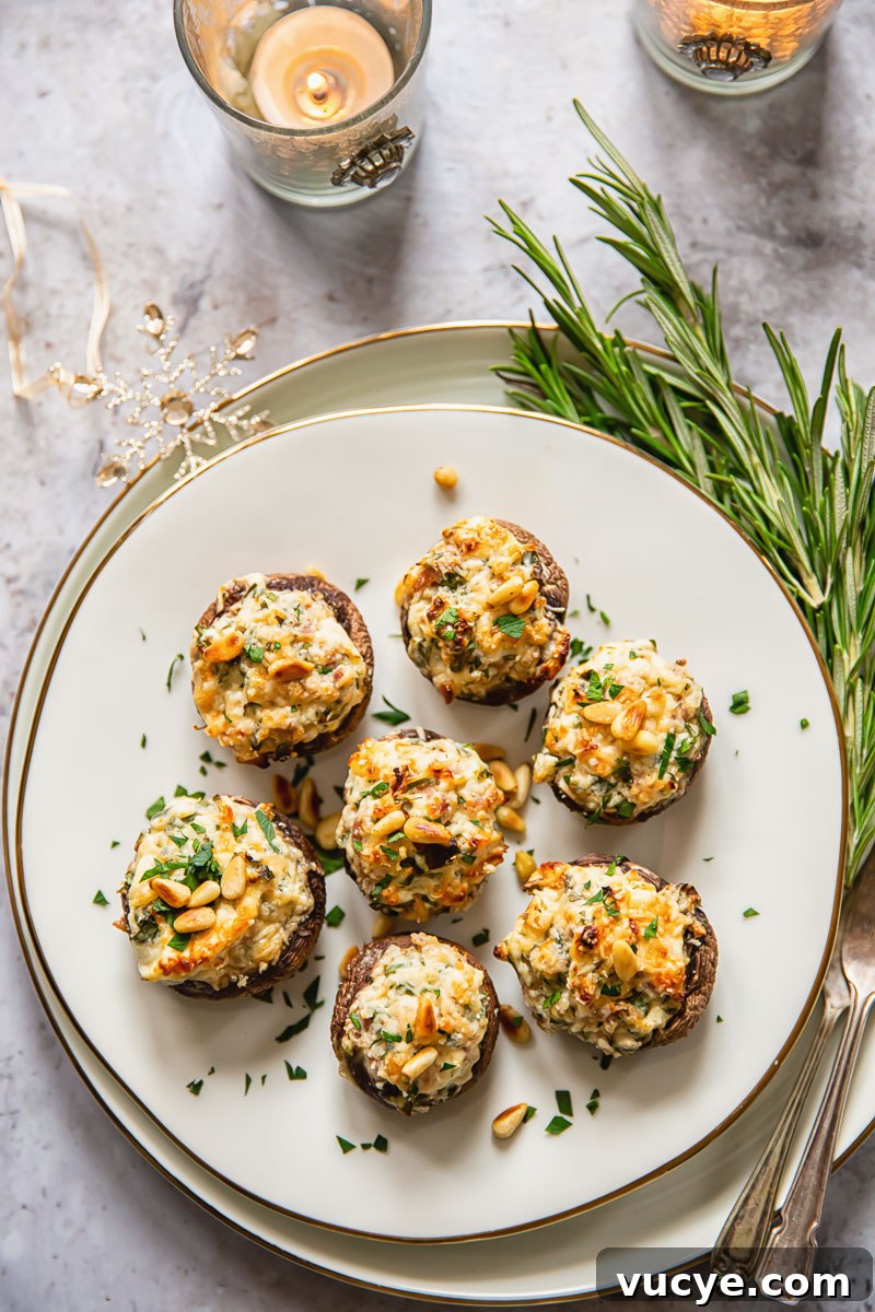 stuffed mushrooms on golden rimmed plate, rosemary and tea candles on marble background