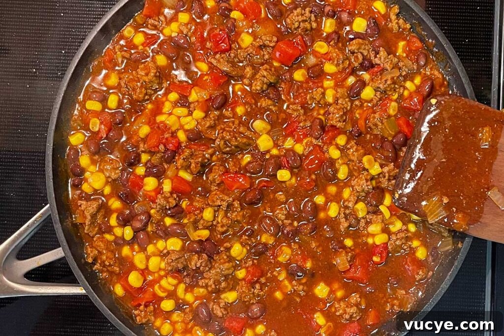 Cheesy Frito Pie Casserole with Chili and Corn Chips 5 Frito pie mixture cooking on stovetop