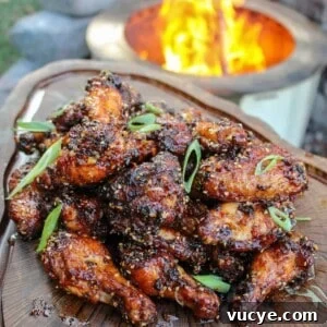 overhead of a platter filled with honey chili oil chicken wings next to a fire