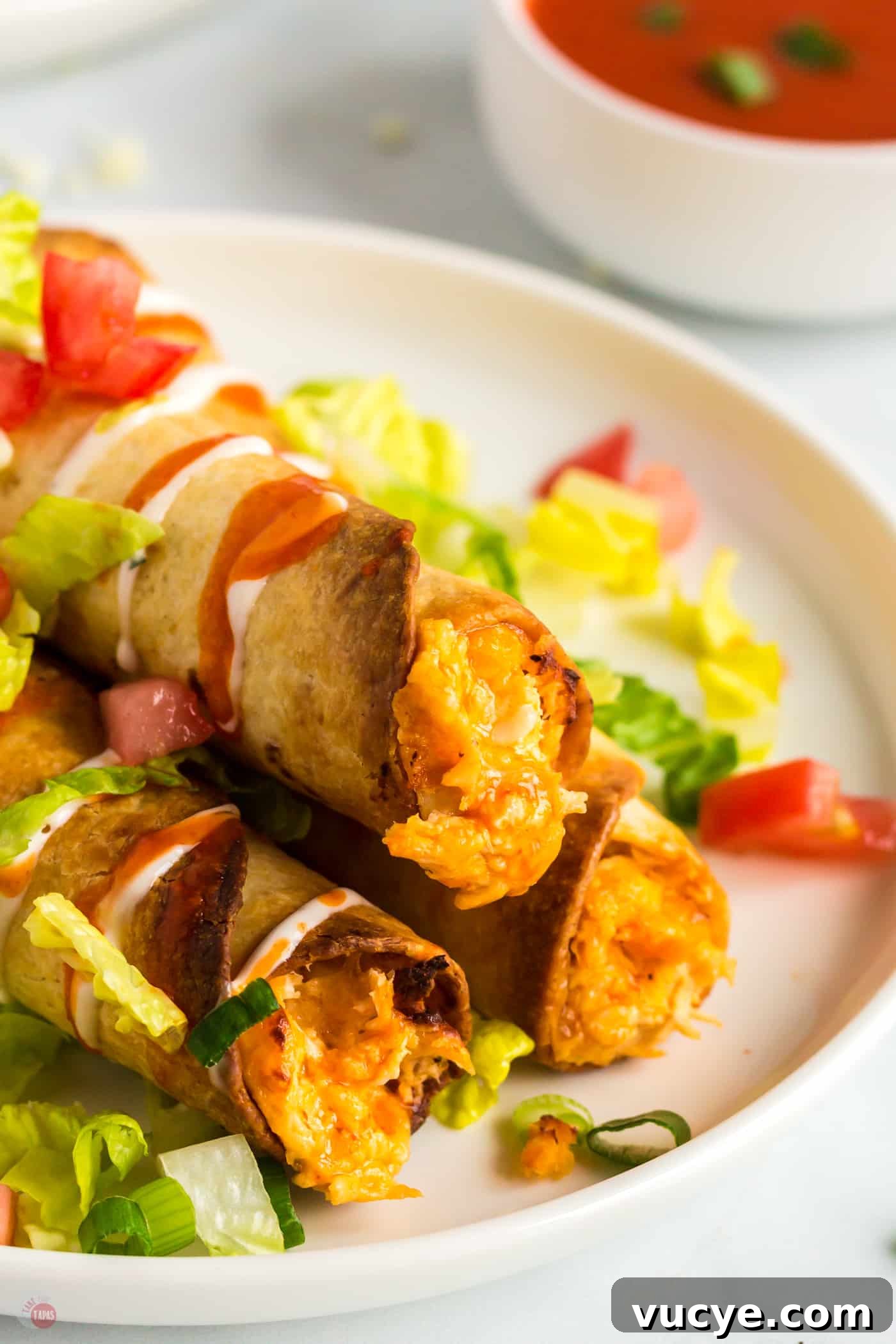 plate with three taquitos and lettuce