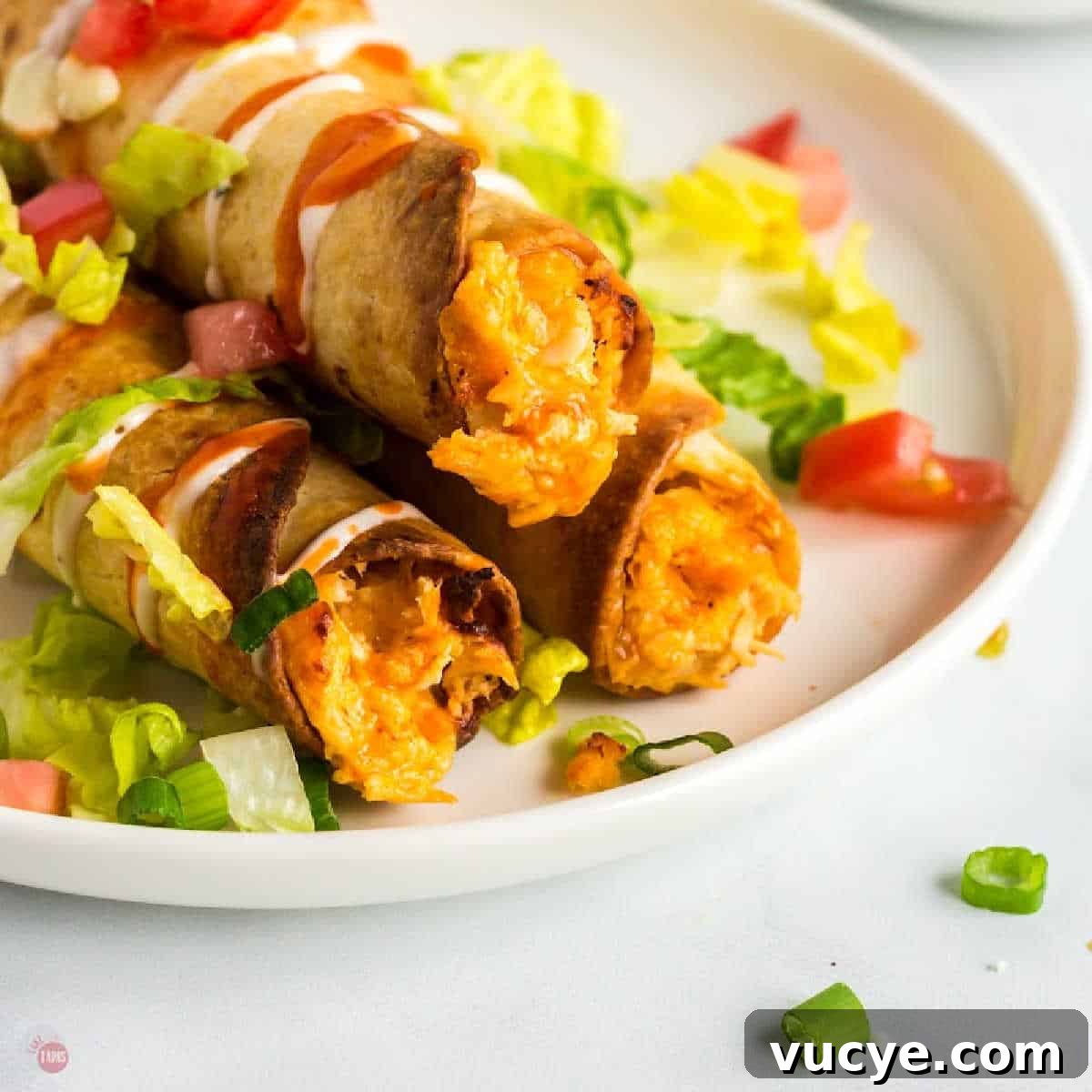 three buffalo chicken taquitos on a plate with lettuce