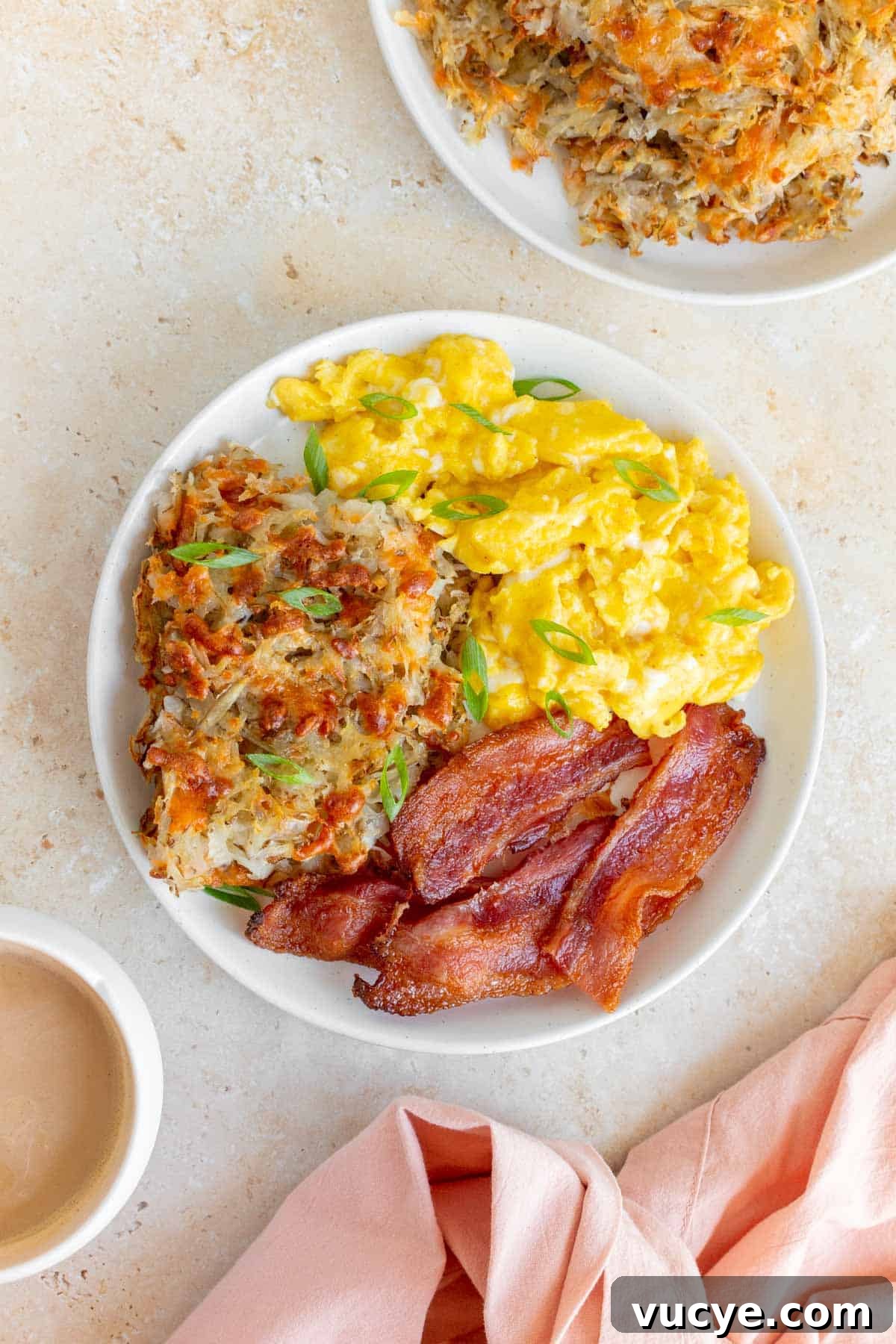 A plate with sheet pan hash browns, scrambled eggs, and bacon.