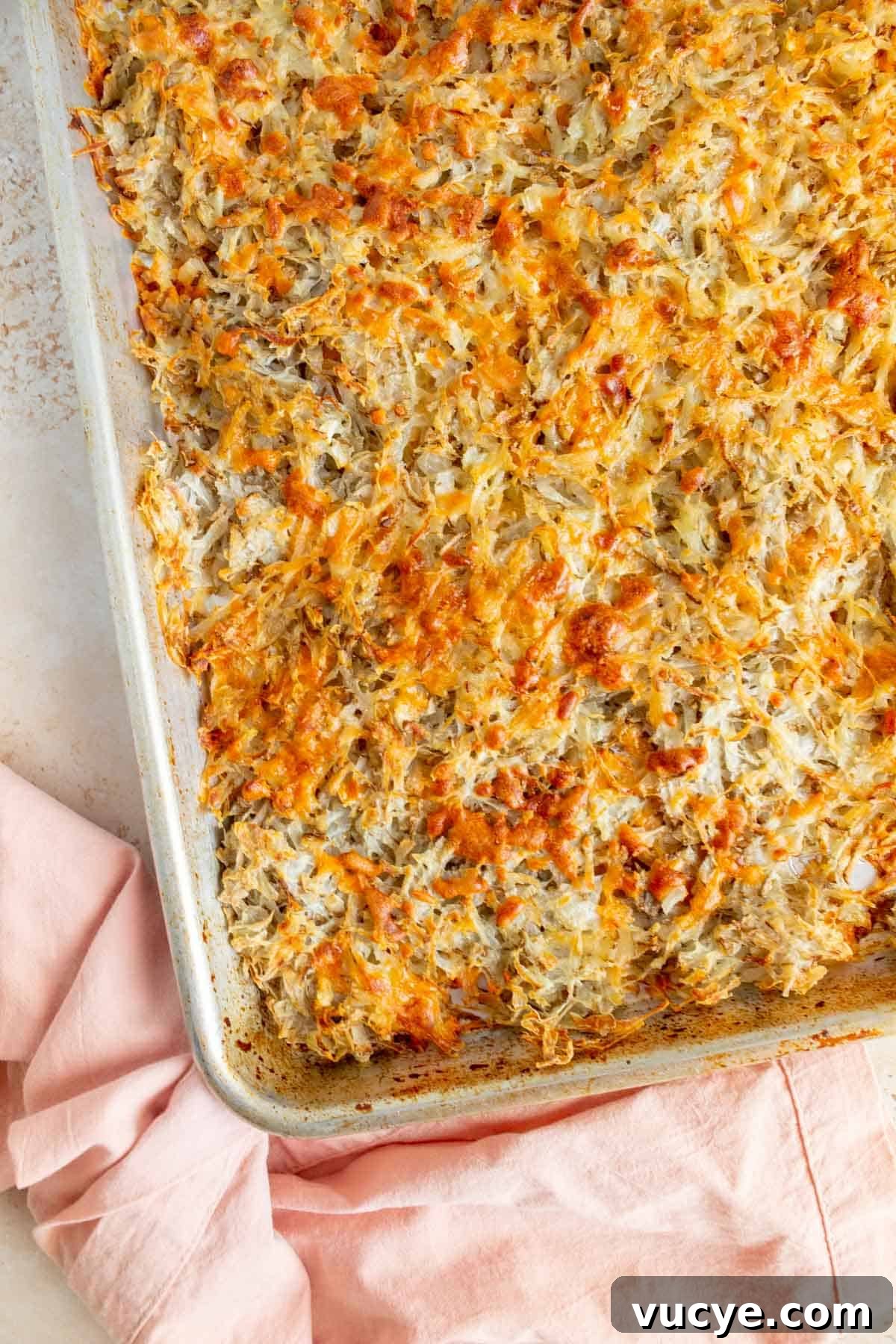 Overhead view of sheet pan hash browns with a pink linen off to the side.