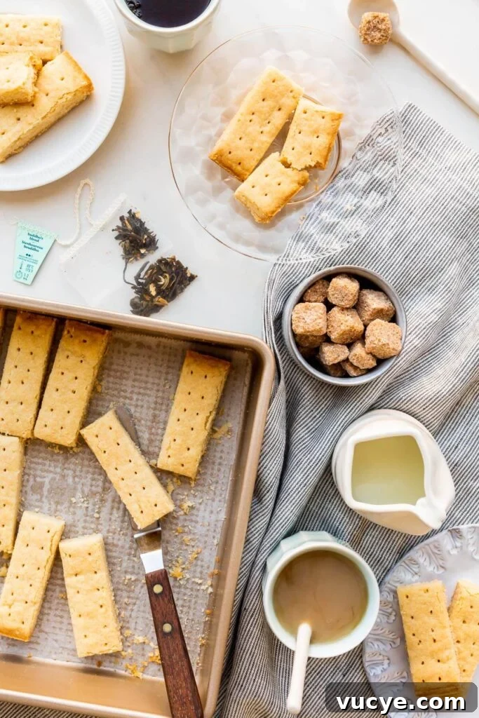 Shortbread cookies being served on small plates with cups of tea, milk, and sugar cubes.