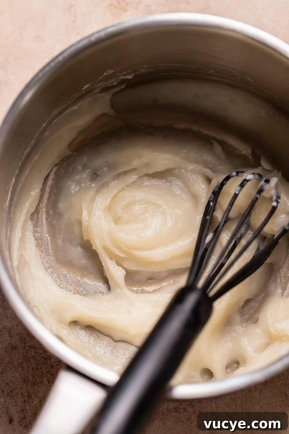 Ultra-Soft Gingerbread Cinnamon Rolls with Molasses Swirl 3 Tangzhong being whisked in a pot with a black whisk.