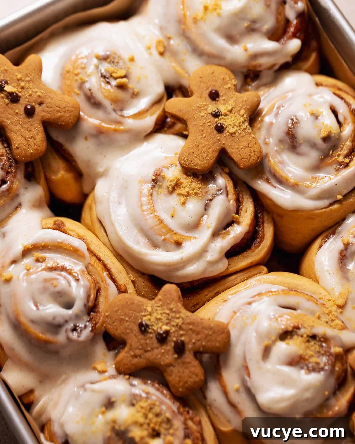 Ultra-Soft Gingerbread Cinnamon Rolls with Molasses Swirl 10 Gingerbread rolls with cream cheese icing in a baking pan.