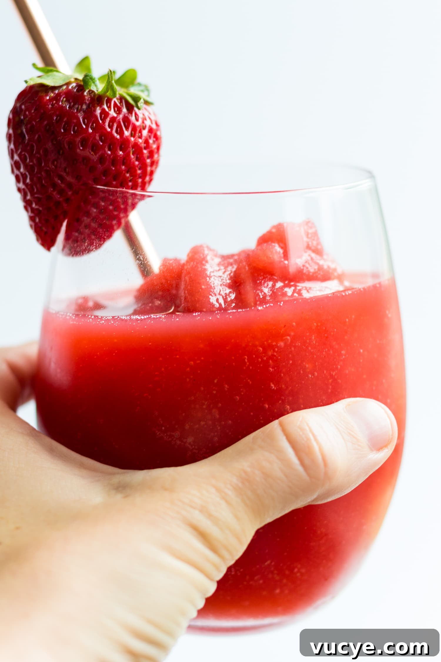 Must-Try Strawberry Recipes for Every Season 15 Hand holding glass of strawberry wine slushie.