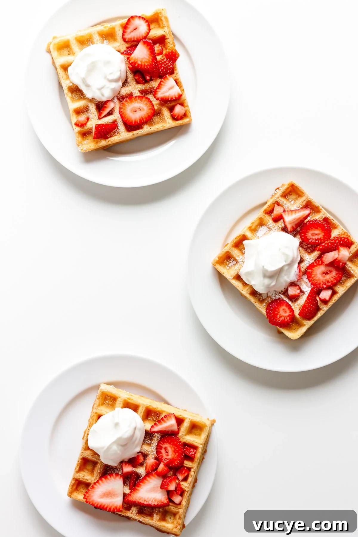 Must-Try Strawberry Recipes for Every Season 16 Three white plates each holding one square waffle topped with fresh strawberries and whipped cream.