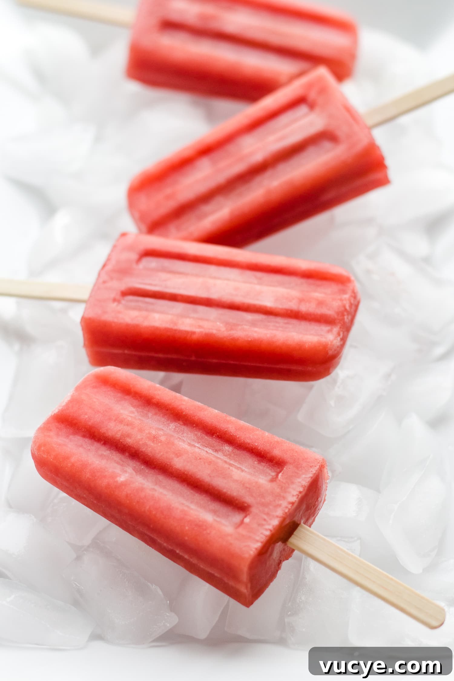 Must-Try Strawberry Recipes for Every Season 9 Four watermelon strawberry popsicles sitting on a bed of ice.