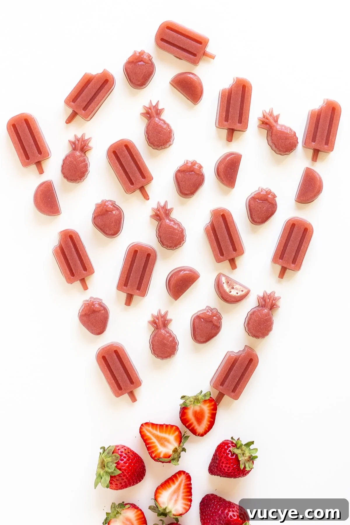 Must-Try Strawberry Recipes for Every Season 10 Variety of homemade strawberry gummies on a white background in the shape of popsicles, pineapples, watermelon slices and strawberries.