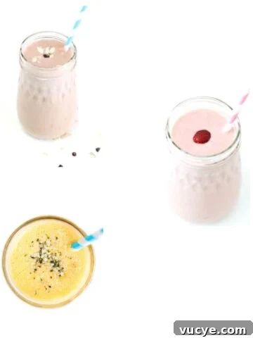 Three different smoothies in glass jars with striped straws.