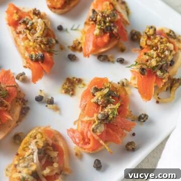 Smoked salmon crostini appetizer with capers and dill on plate.