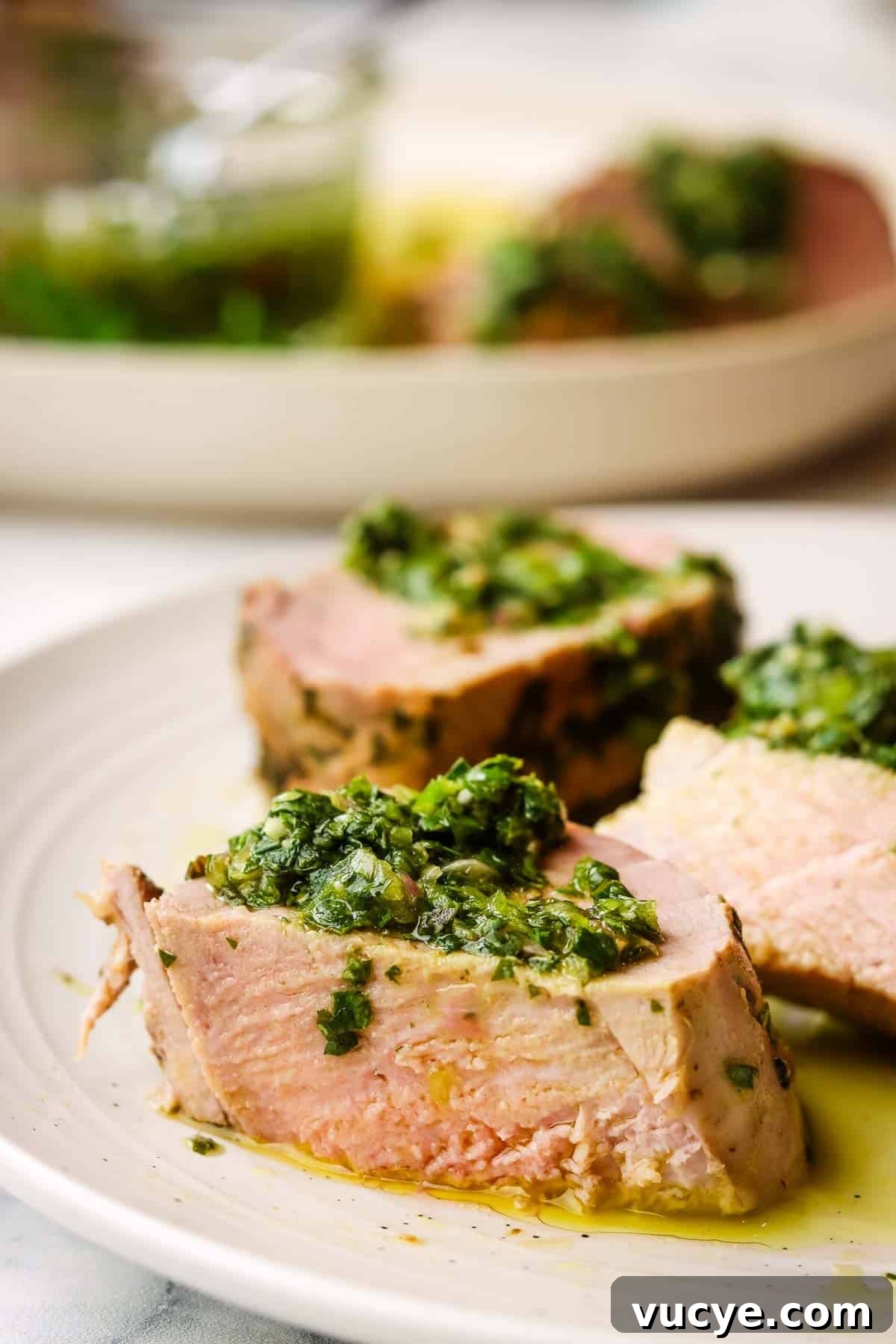 Grilled Pork Tenderloin with Chimichurri Sauce 11 grilled pork tenderloin slices served on a plate with chimichurri on top.