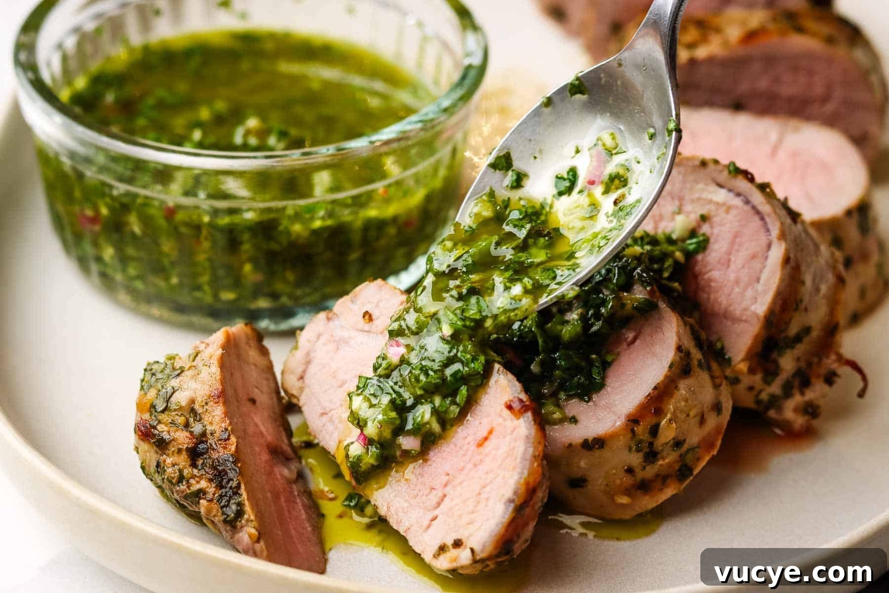 Grilled Pork Tenderloin with Chimichurri Sauce 13 Spooning chimichurri over a plate of sliced pork tenderloin.