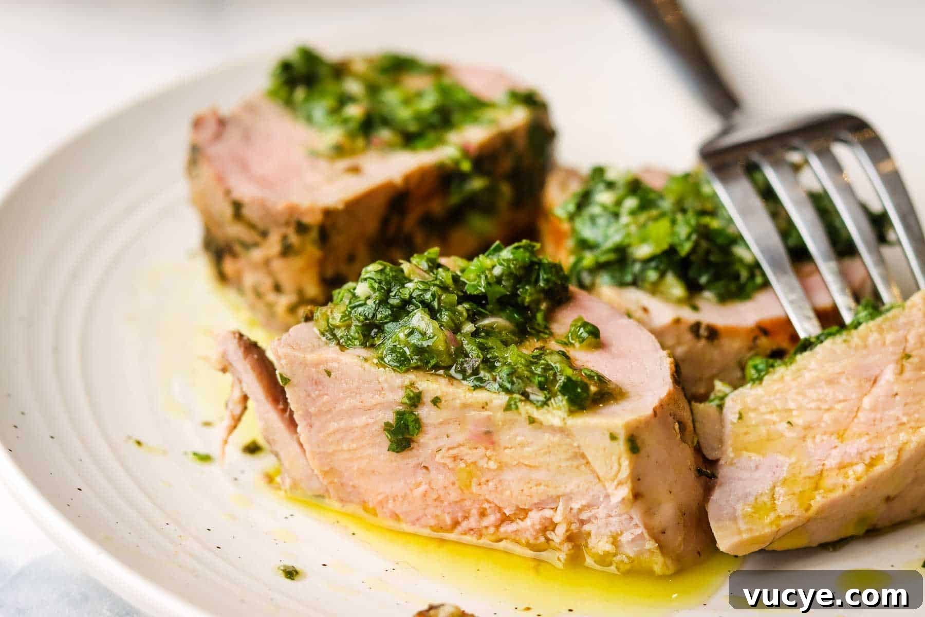 Grilled Pork Tenderloin with Chimichurri Sauce 3 A plate of sliced pork tenderloin with chimichurri on top.