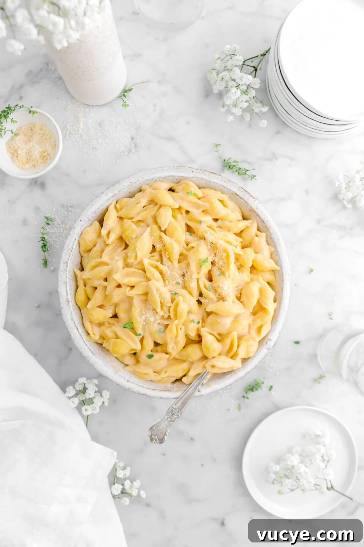 Creamy Four-Cheese Macaroni and Cheese Recipe 4 overhead shot of bowl of macaroni and cheese with fork dug inside, flowers and thyme sprigs around