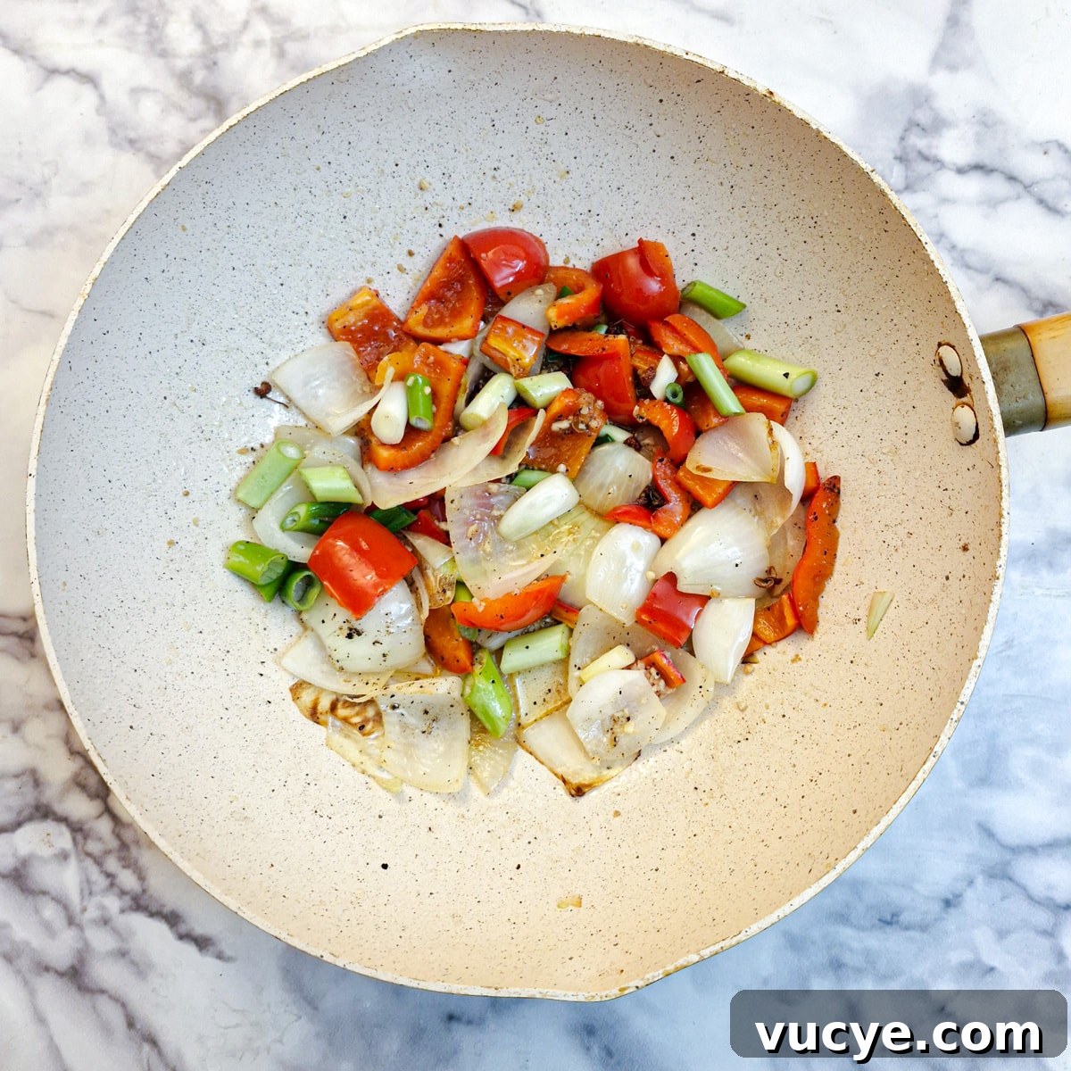 Crispy Salt and Pepper Chicken Recipe for Dinner 12 Onions and red peppers with chopped green spring onions frying in a wok.