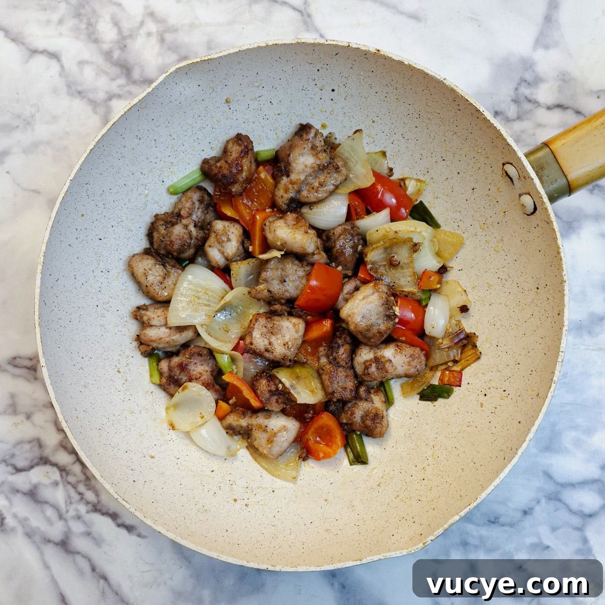 Crispy Salt and Pepper Chicken Recipe for Dinner 13 Fried chicken pieces mixed with onions and red peppers in a wok.
