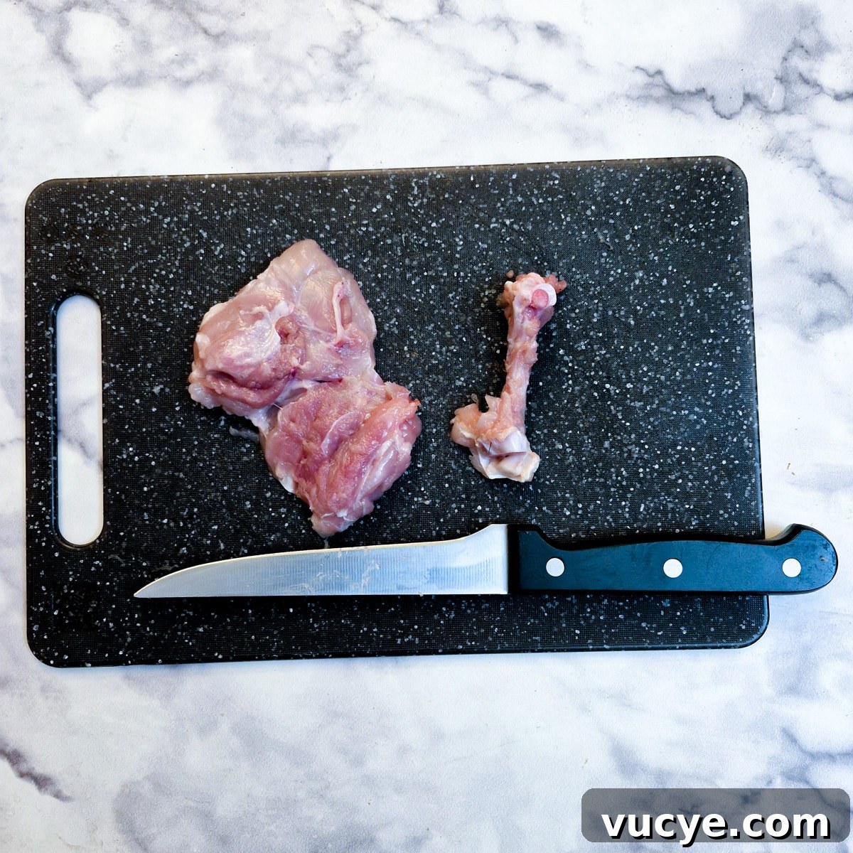 Crispy Salt and Pepper Chicken Recipe for Dinner 6 A deboned chicken thigh on a chopping board next to the bone that has been removed.