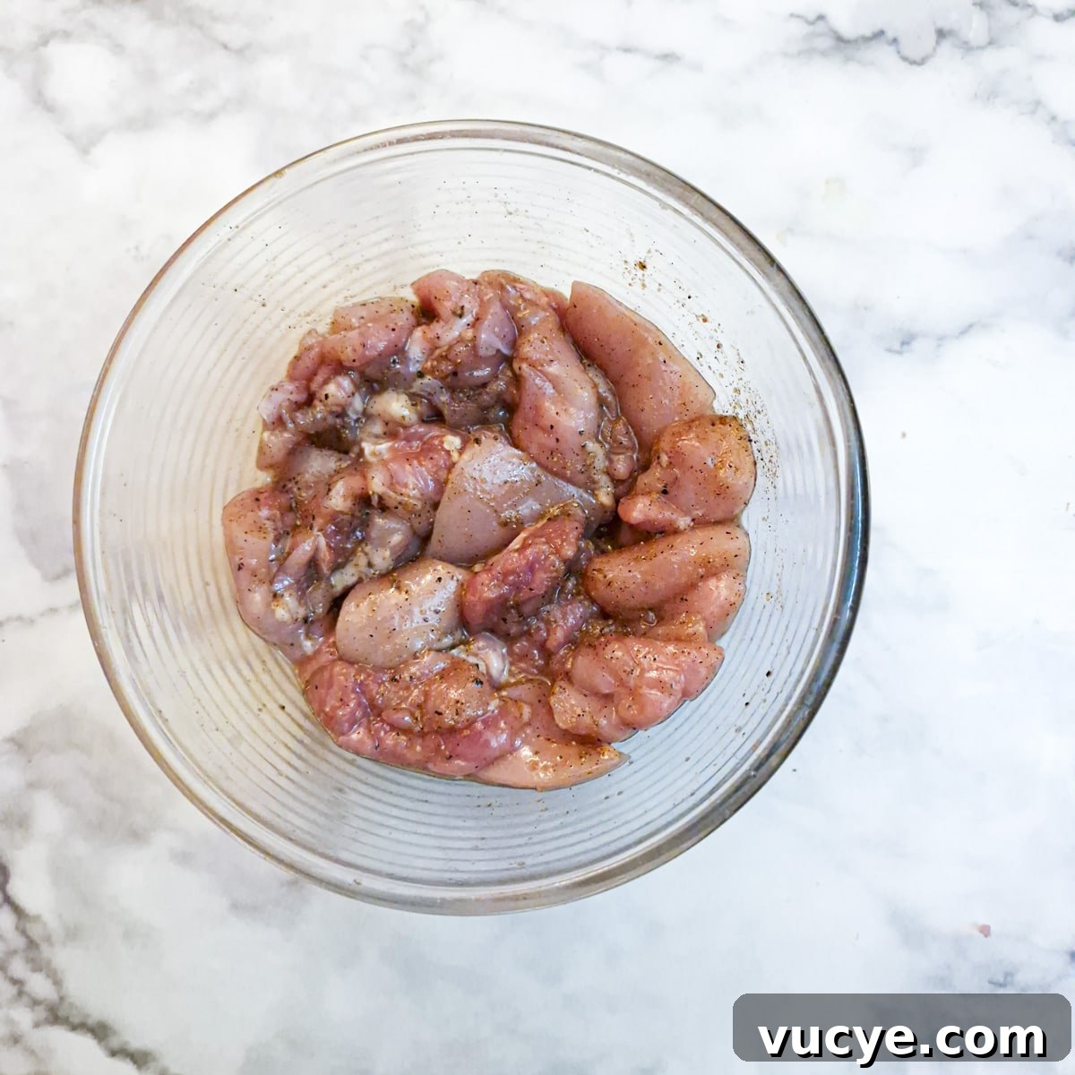 Crispy Salt and Pepper Chicken Recipe for Dinner 7 A glass dish with chicken pieces mixed into a marinade.