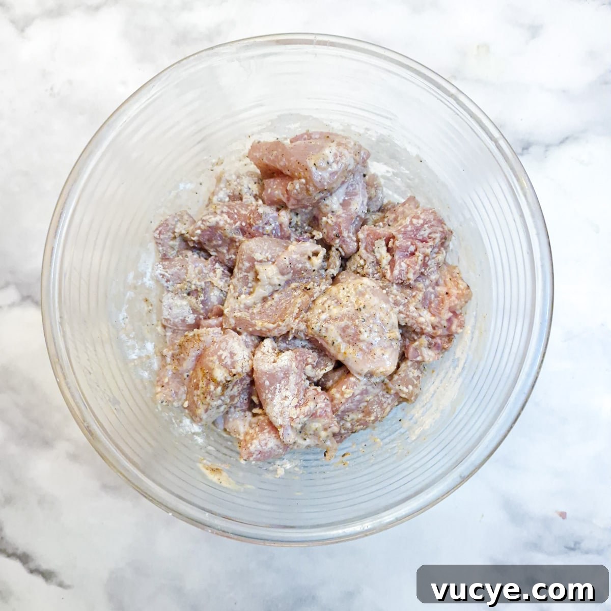 Crispy Salt and Pepper Chicken Recipe for Dinner 8 A glass bowl with pieces of marinated chicken coated in cornflour.